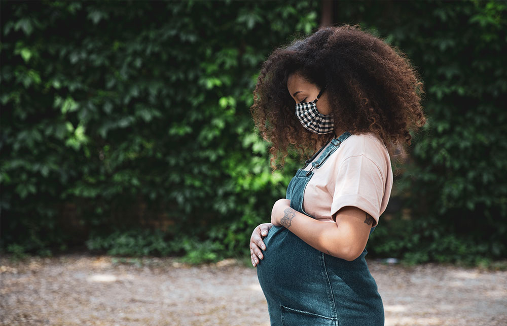 Black pregnant mother looking down at her belly.