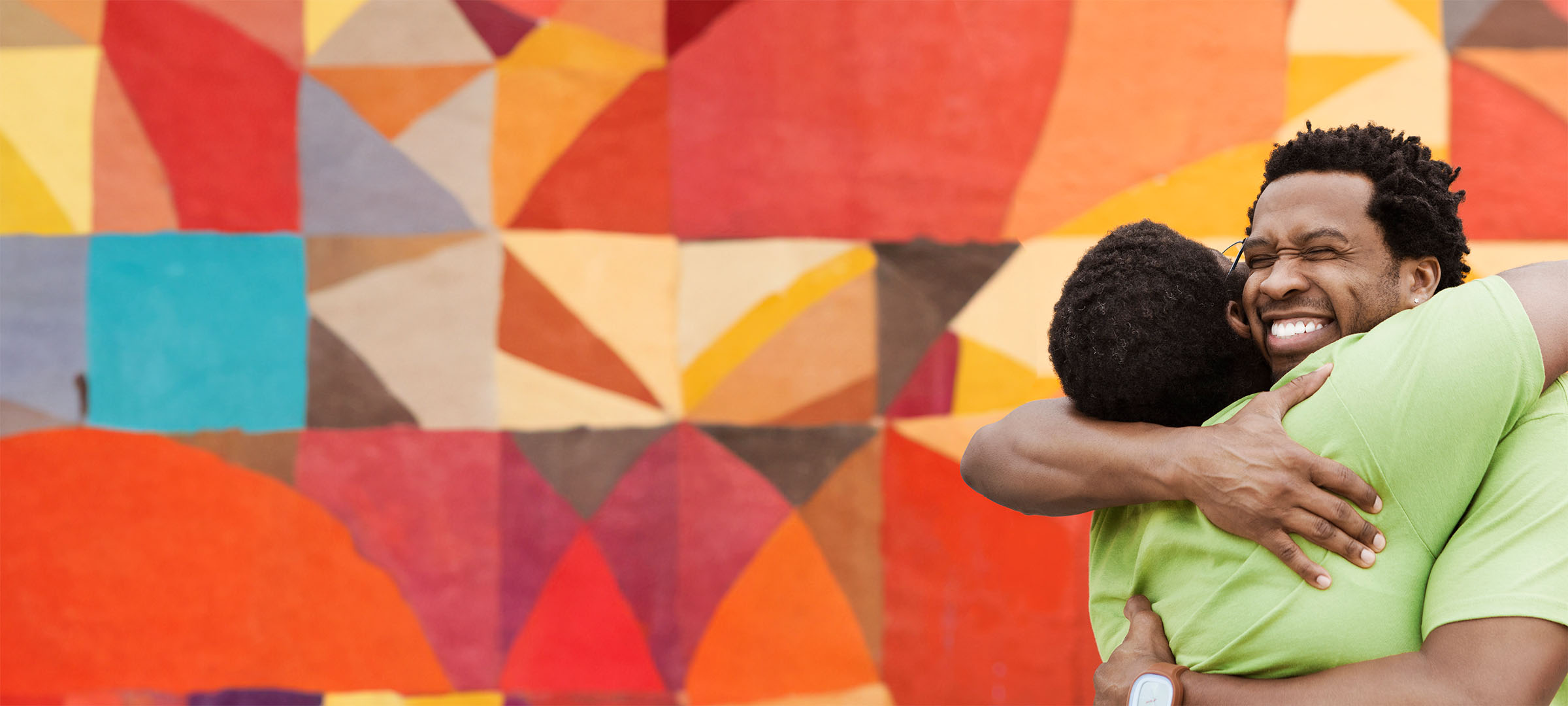 Two friends hugging in front of a mural Two friends hugging in front of a mural