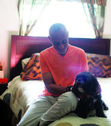 Thomas Wilkins sits in his stylish bedroom holding his small dog, Apollo