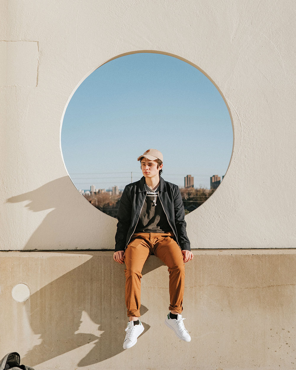 A teenager sitting on top of a public art sculpture.